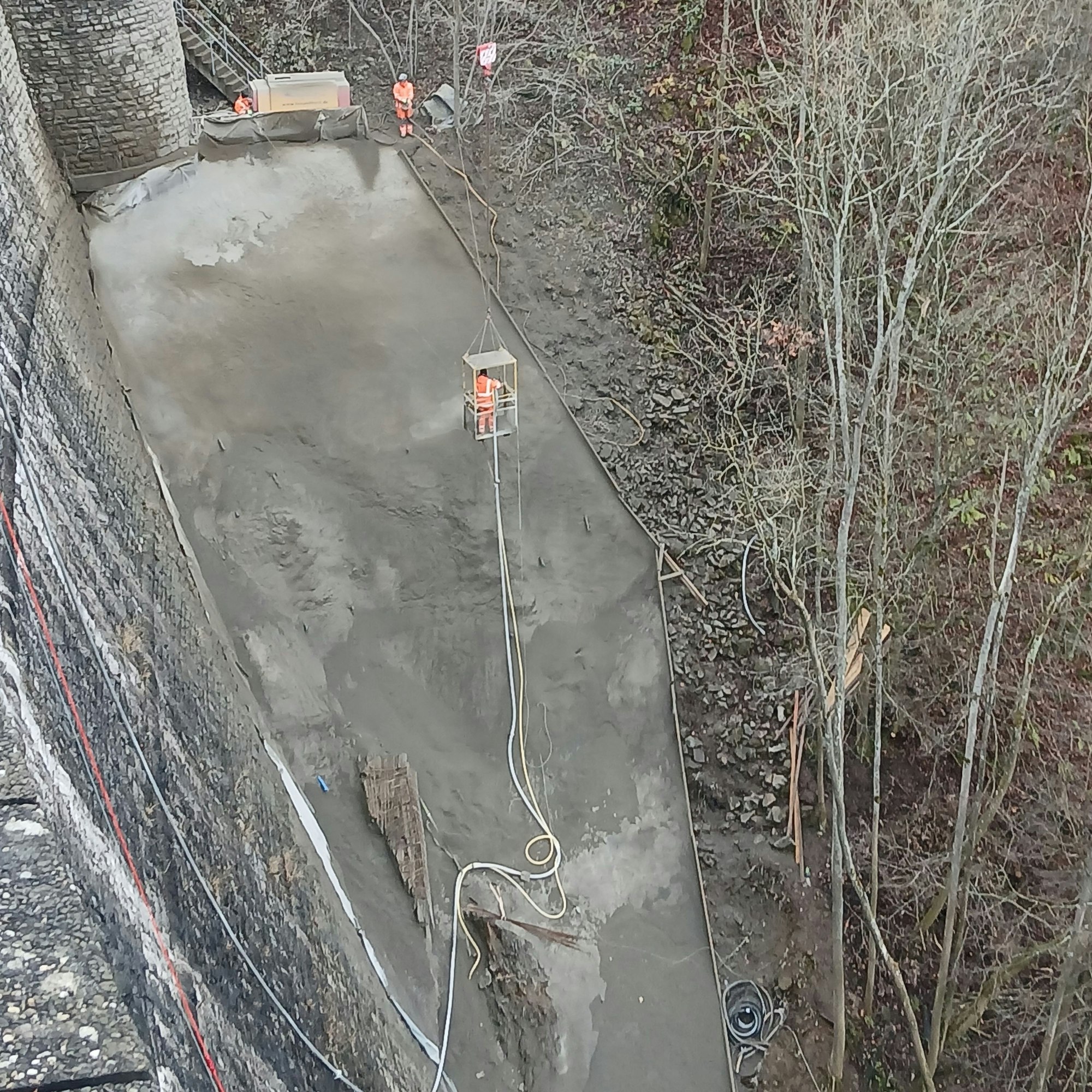 Blick auf den Hang neben der Urftstaumauer, der von Arbeitern mit Beton gesichert wird.