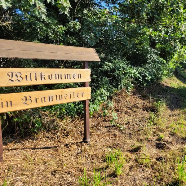 Ein Willkommensschild aus Holz begrüßt Einheimische und Zugereiste in Brauweiler.