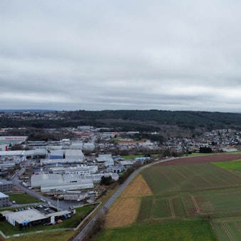 Blick aus der Vogelperspektive auf die Äcker und Wiesen sowie auf das Gewerbegebiet 2 gegenüber.