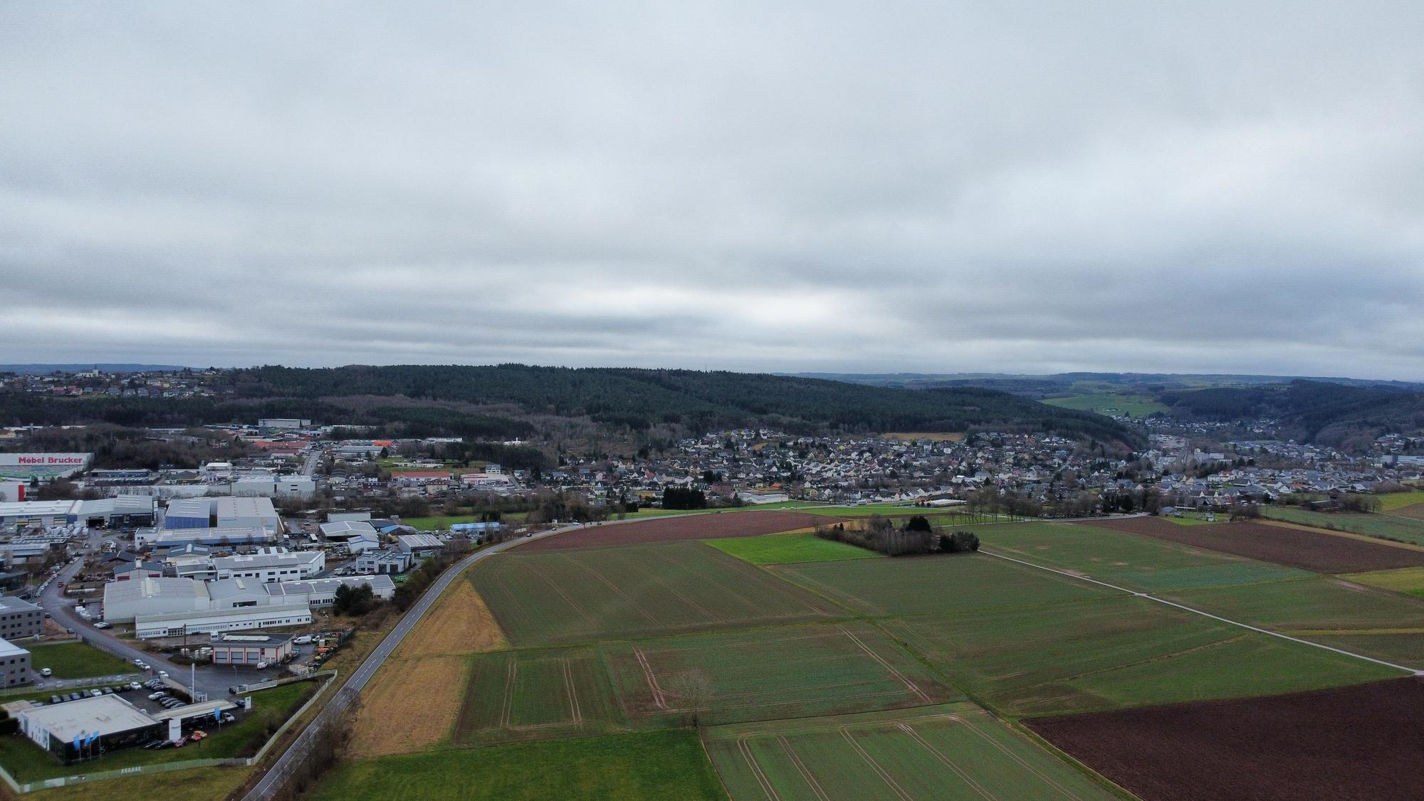 Blick aus der Vogelperspektive auf die Äcker und Wiesen sowie auf das Gewerbegebiet 2 gegenüber.