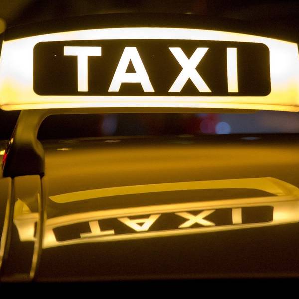 Ein Taxi steht mit leuchtendem „Taxi“-Schild für Fahrgäste bereit.