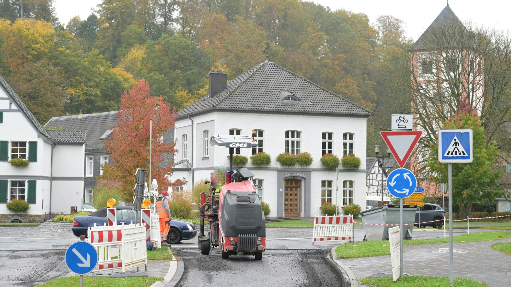 Am Kreisverkehr vor dem Odenthaler Rathaus fräst eine Baumaschine die Asphaltdecke ab.