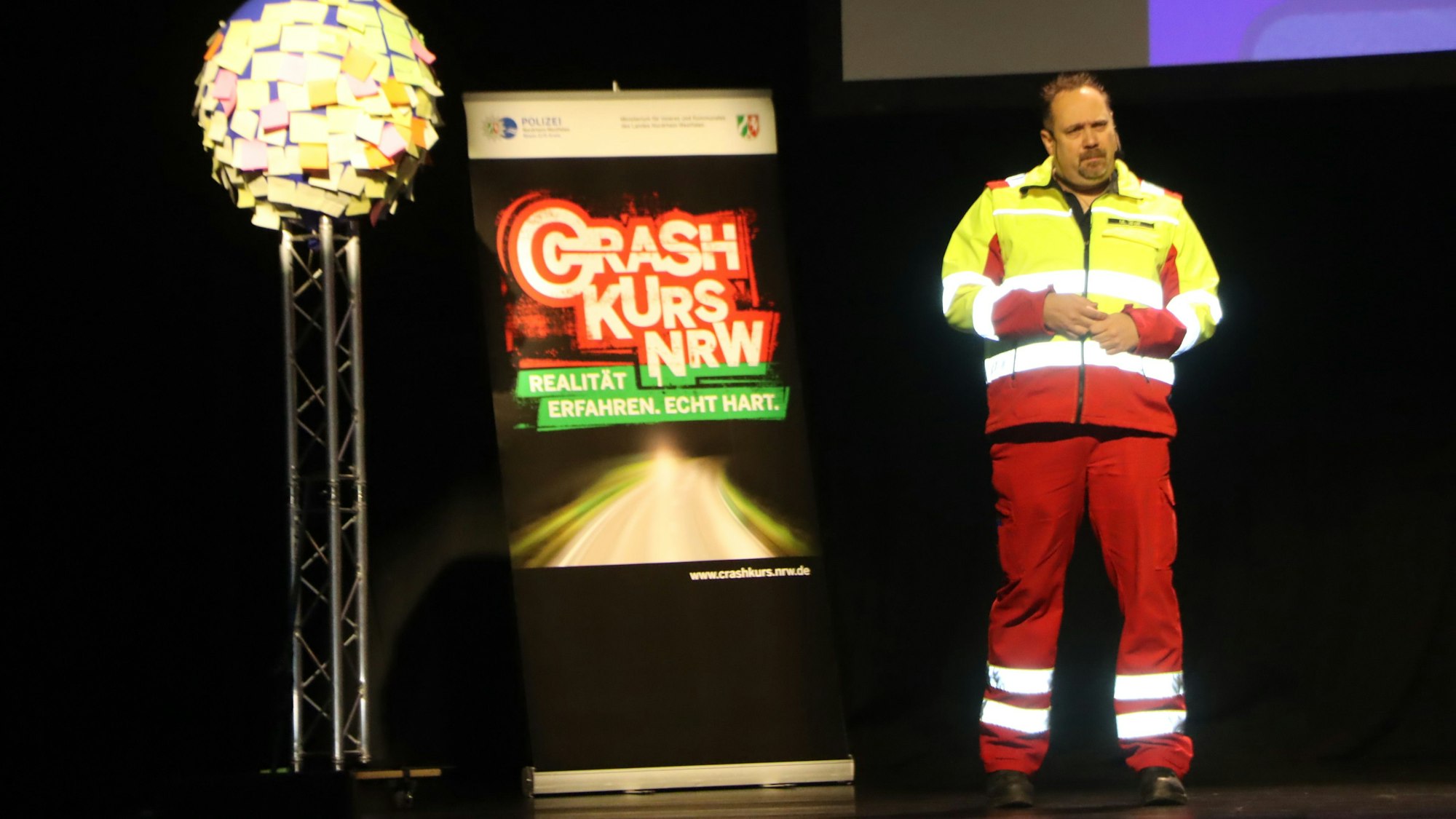 Auf einer Bühne steht ein Feuerwehrmann.