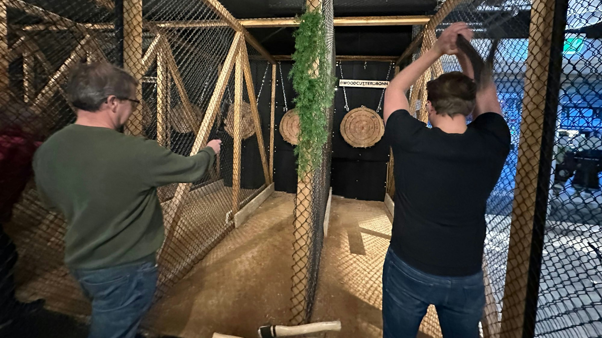 Zwei Männer werfen mit Äxten auf Zielscheiben.