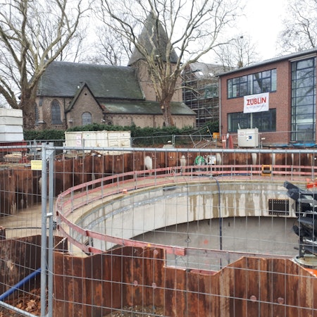 Ansicht auf die zylinderförmige Baugrube, im Hintergrund Alt St. Katharina und der Grundschul-Erweiterungsbau.