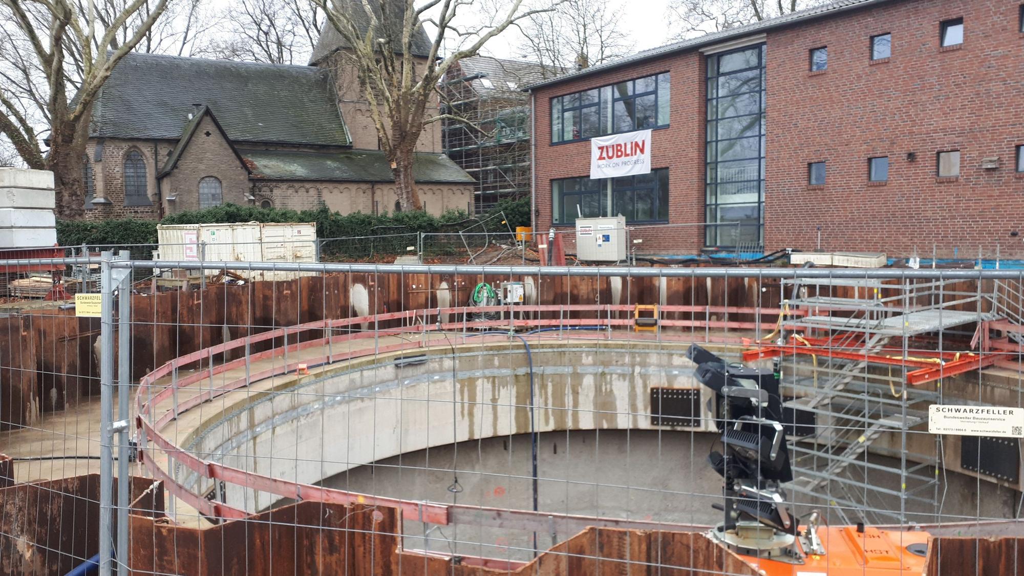 Ansicht auf die zylinderförmige Baugrube, im Hintergrund Alt St. Katharina und der Grundschul-Erweiterungsbau.