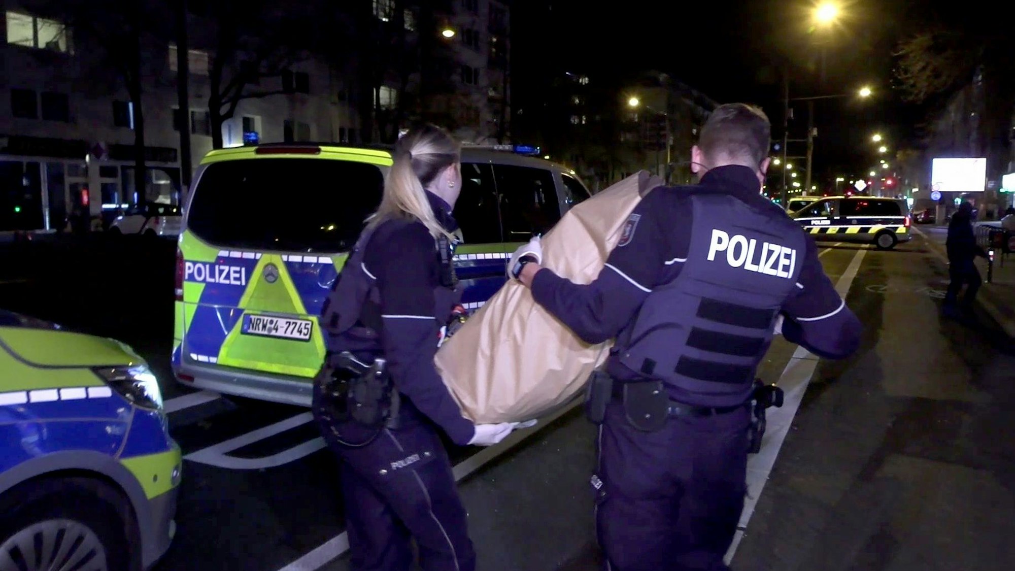 Köln: Polizeikräfte tragen den zurückgelassenen Koffer weg. Wegen eines herrenlosen Koffers im Kassenbereich eines Lebensmittelmarktes hat es am Abend in Köln erneut einen Polizeieinsatz und Absperrungen gegeben.