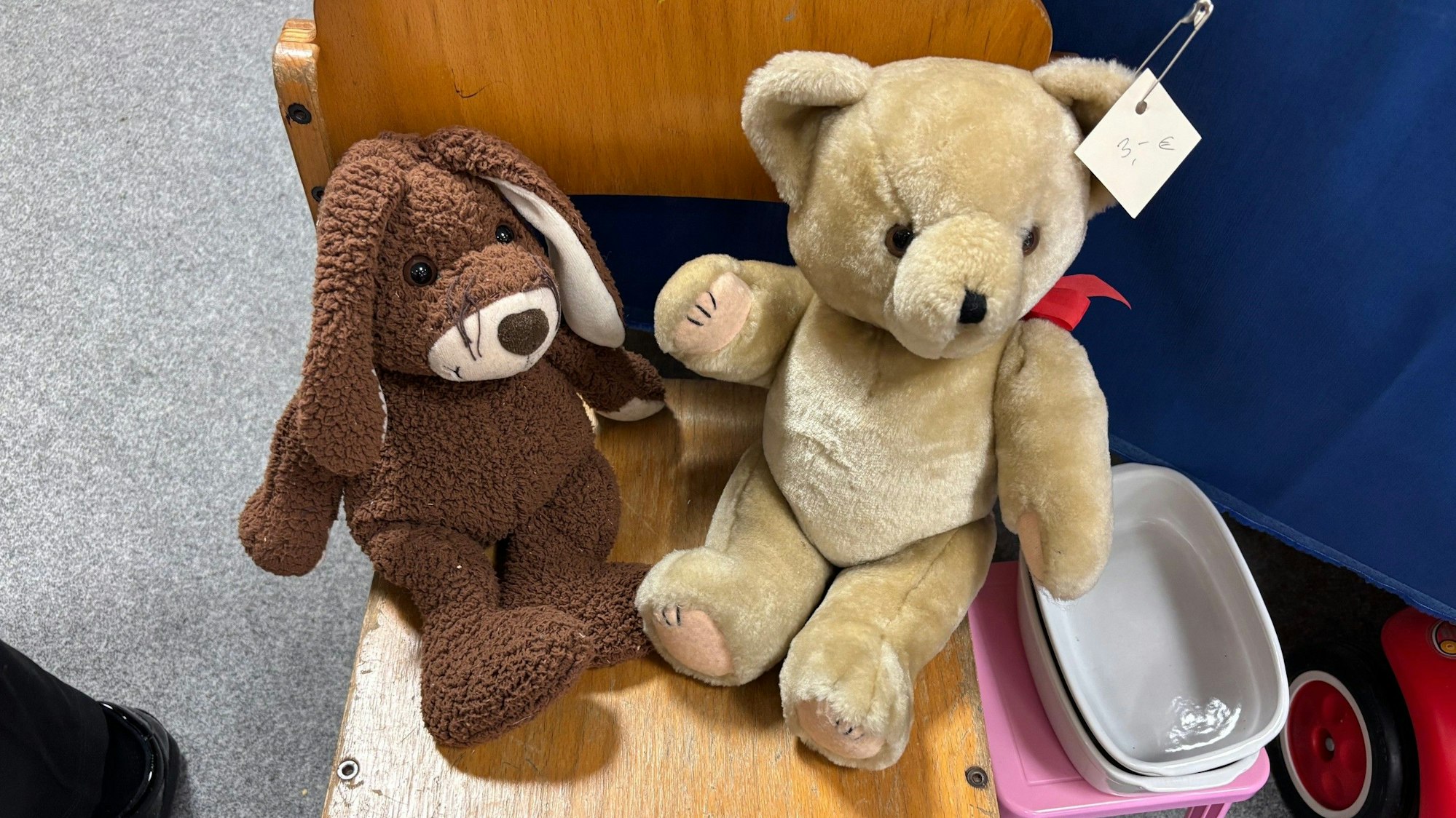 Auf dem Bild sind zwei Stofftiere auf einem Holzstuhl zu sehen.