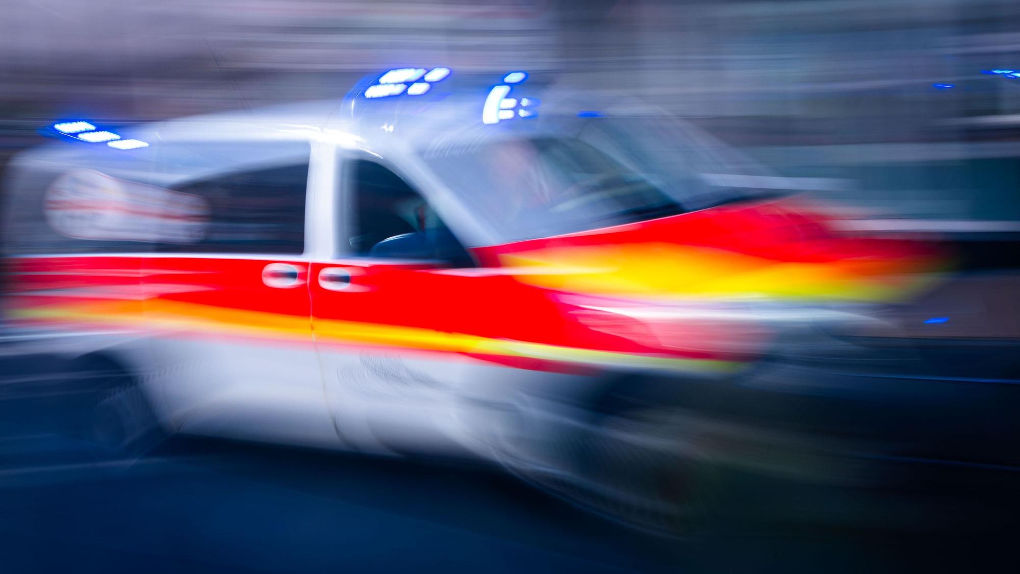 Ein Rettungsfahrzeug ist mit Blaulicht auf einer Straße unterwegs.