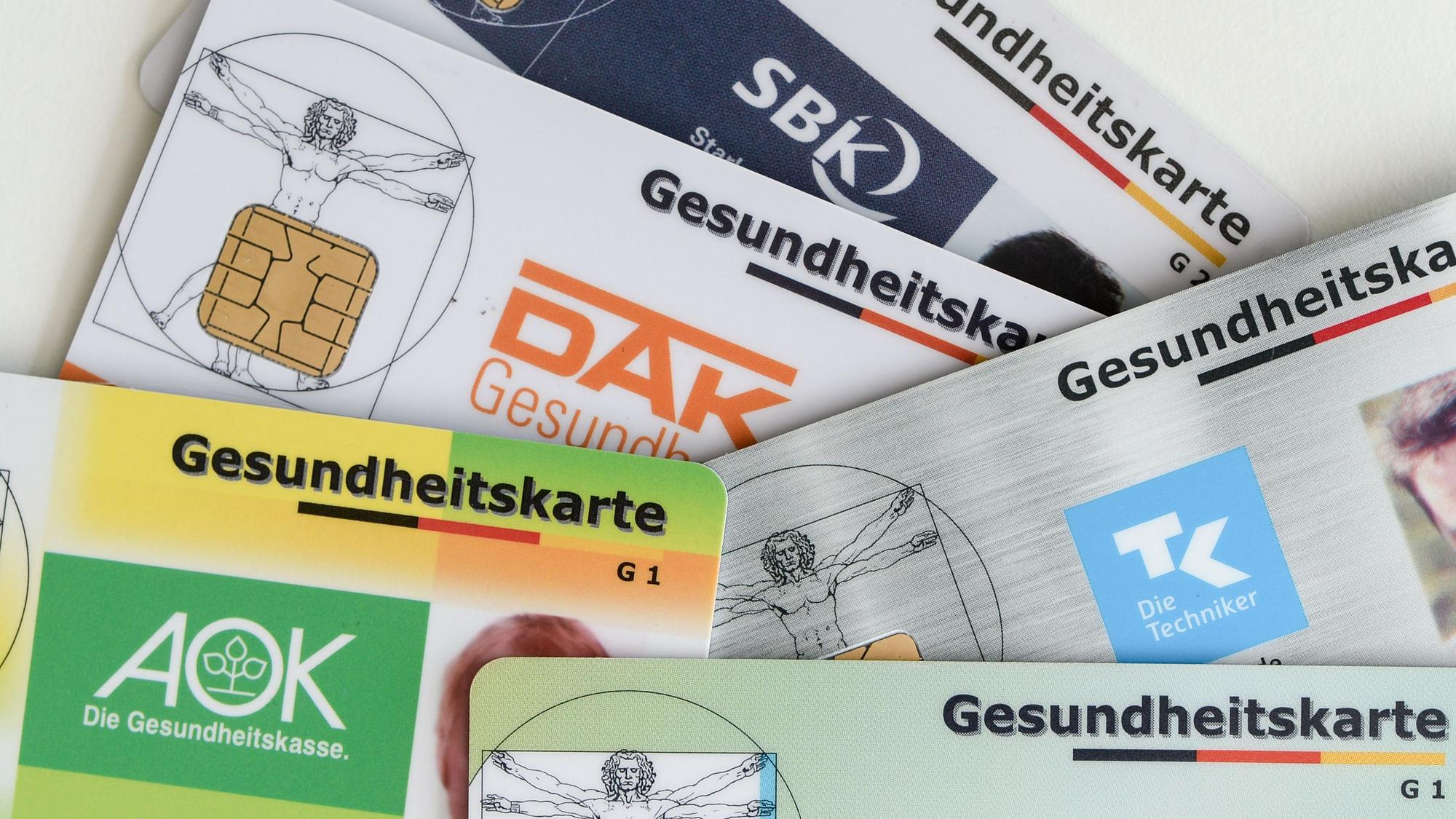 ARCHIV - 17.04.2018, Berlin: Gesundheitskarten verschiedener Krankenkassen liegen auf einem Tisch.
