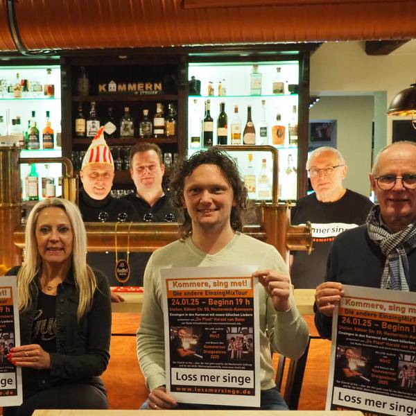 Sechs Männer und eine Frau haben sich vor und hinter der Theke verteilt. Einige von ihnen präsentieren das Veranstaltungsplakat.
