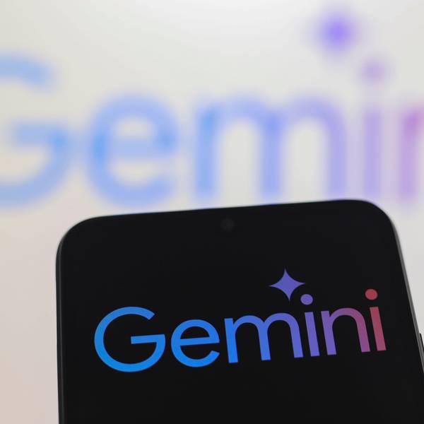 Ein Smartphone mit dem Logo von Gemini vor einer Wand, auf der ebenfalls Gemini steht.