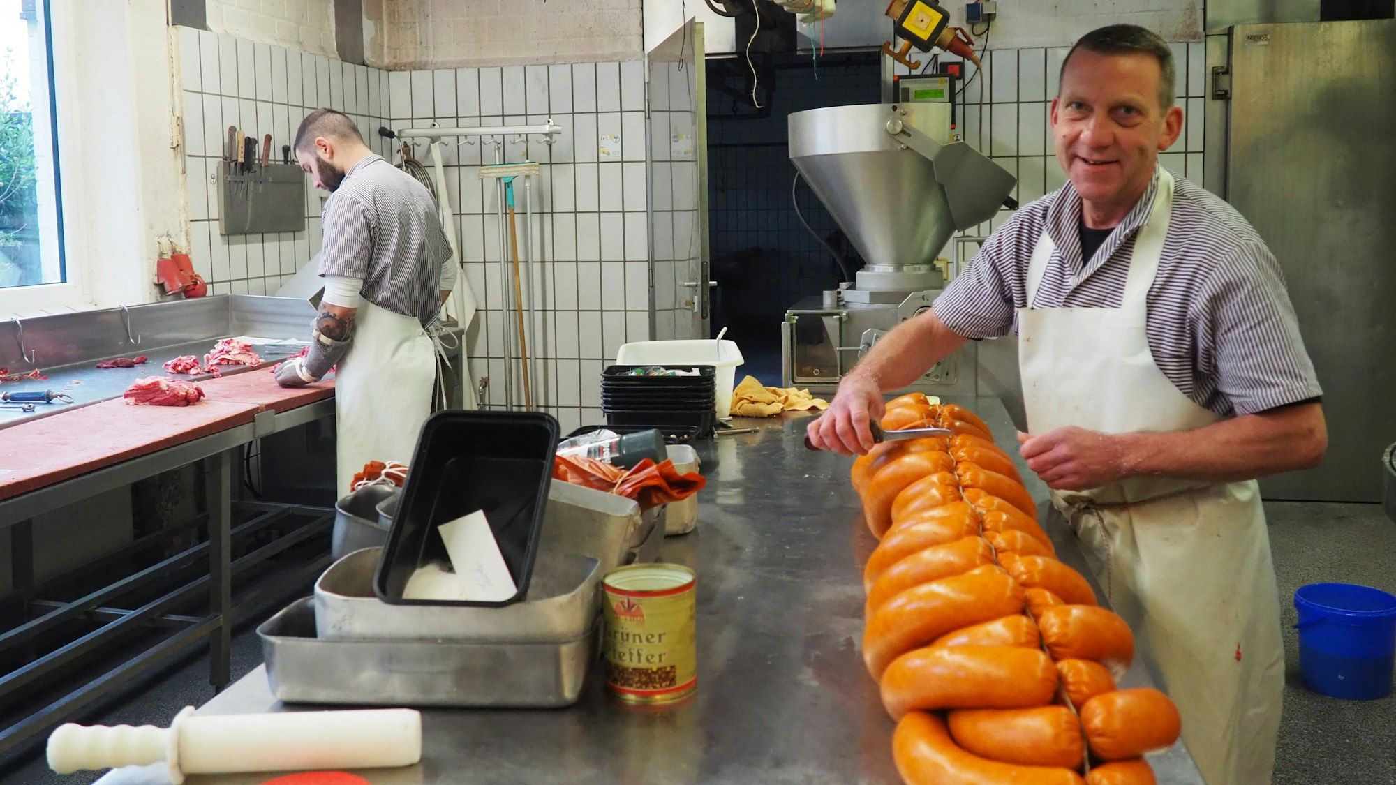 Ein Metzgermeister füllt Wurstmasse in den Darm und formt perfekte Ringe daraus.