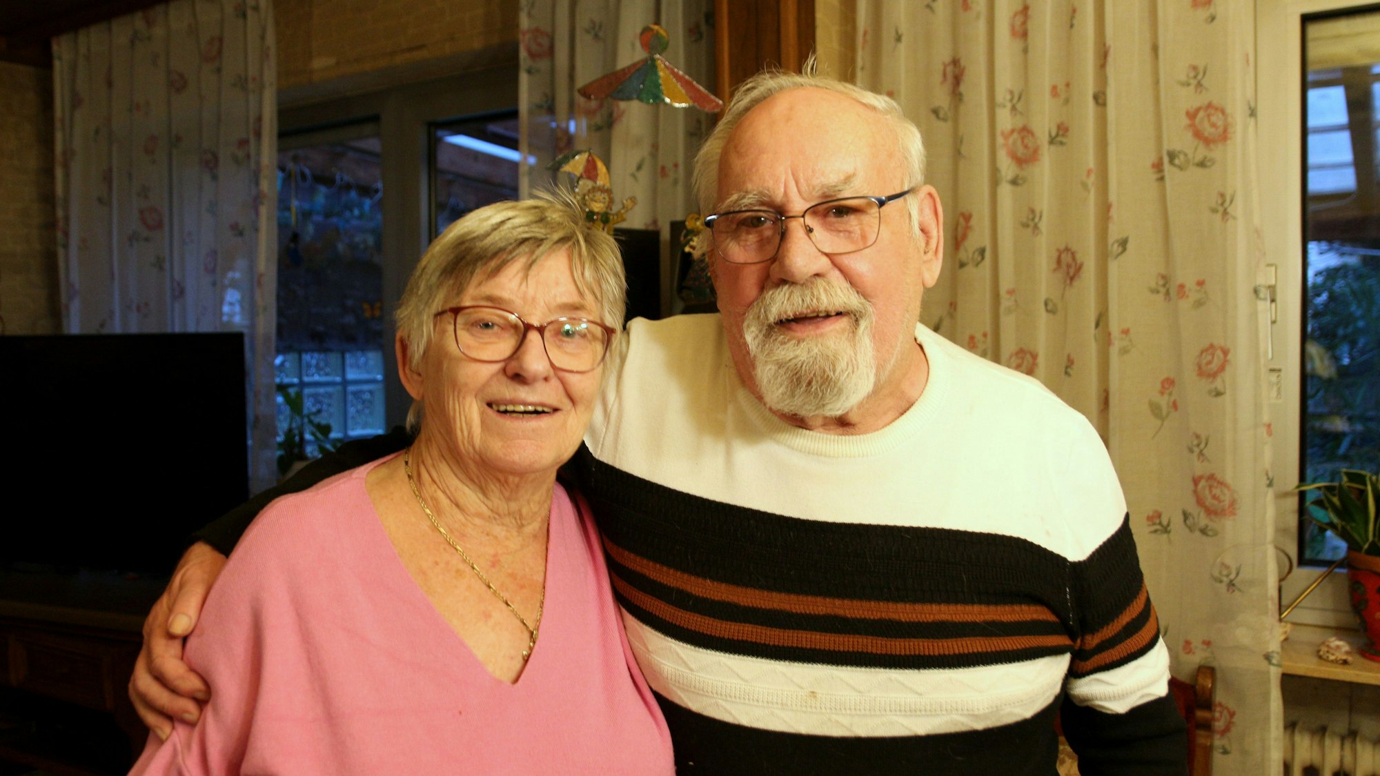 Eine Frau und ein Mann lächeln in die Kamera. Er hat seinen rechten Arm um sie gelegt.