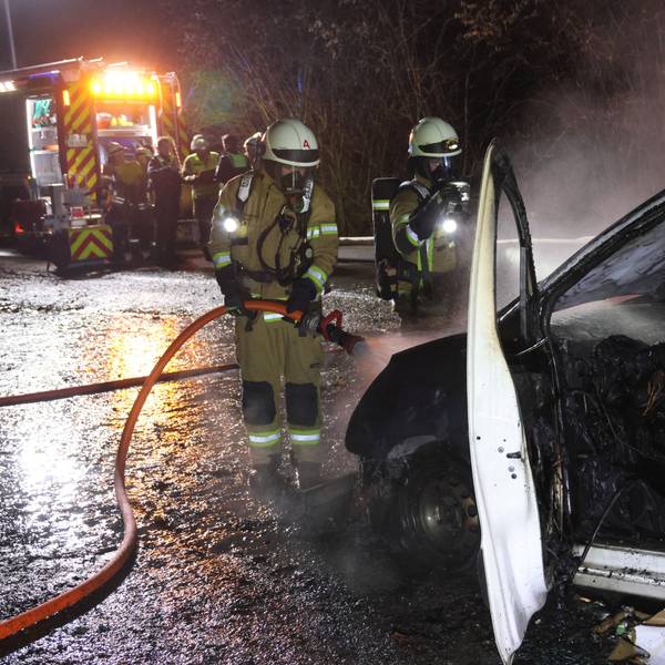 Feuerwehrleute löschen einen brennenden Pkw-Transporter.