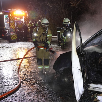 Feuerwehrleute löschen einen brennenden Pkw-Transporter.