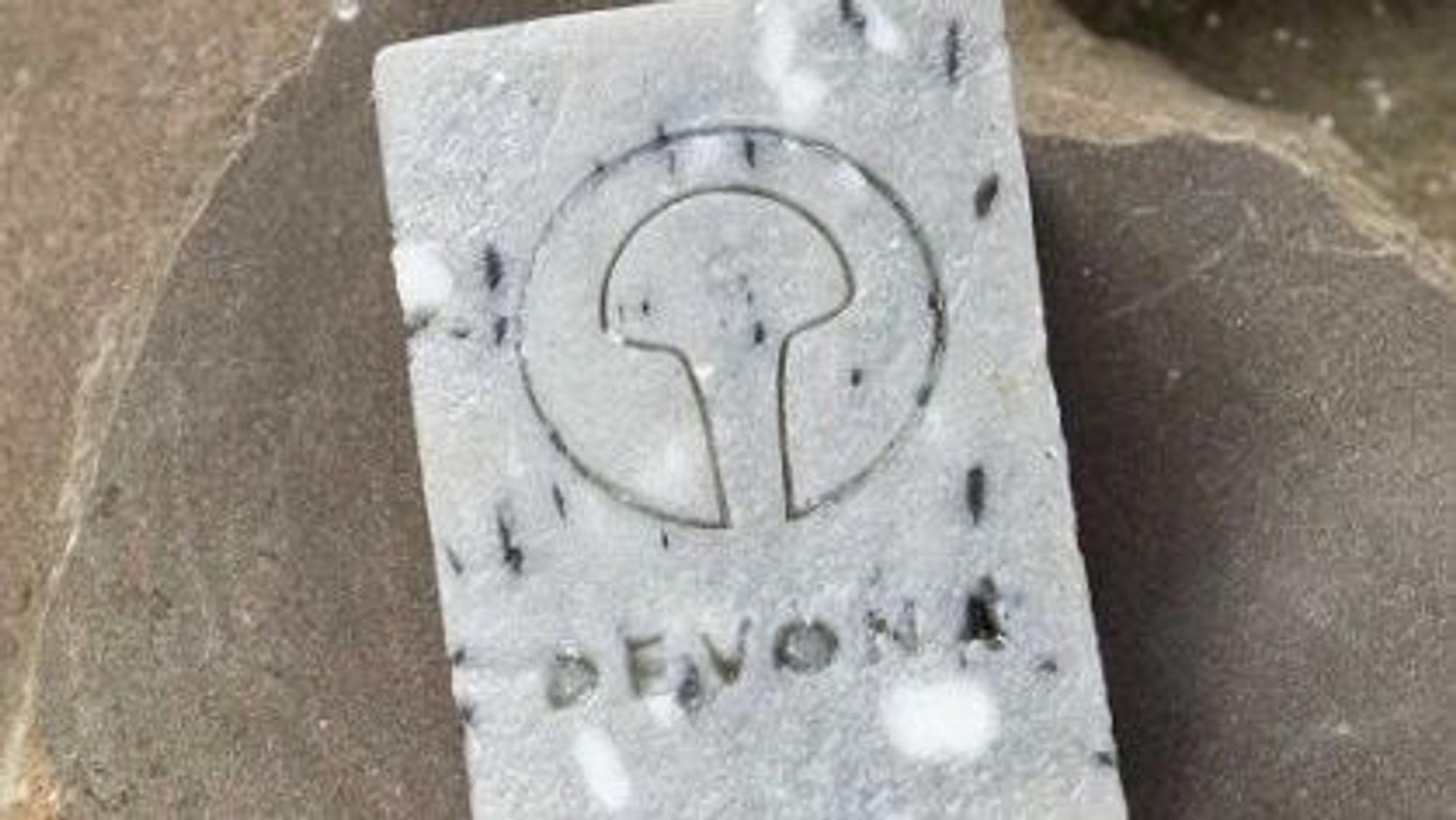 Eine Devona-Grauwackeseife liegt auf einem Grauwackestein.