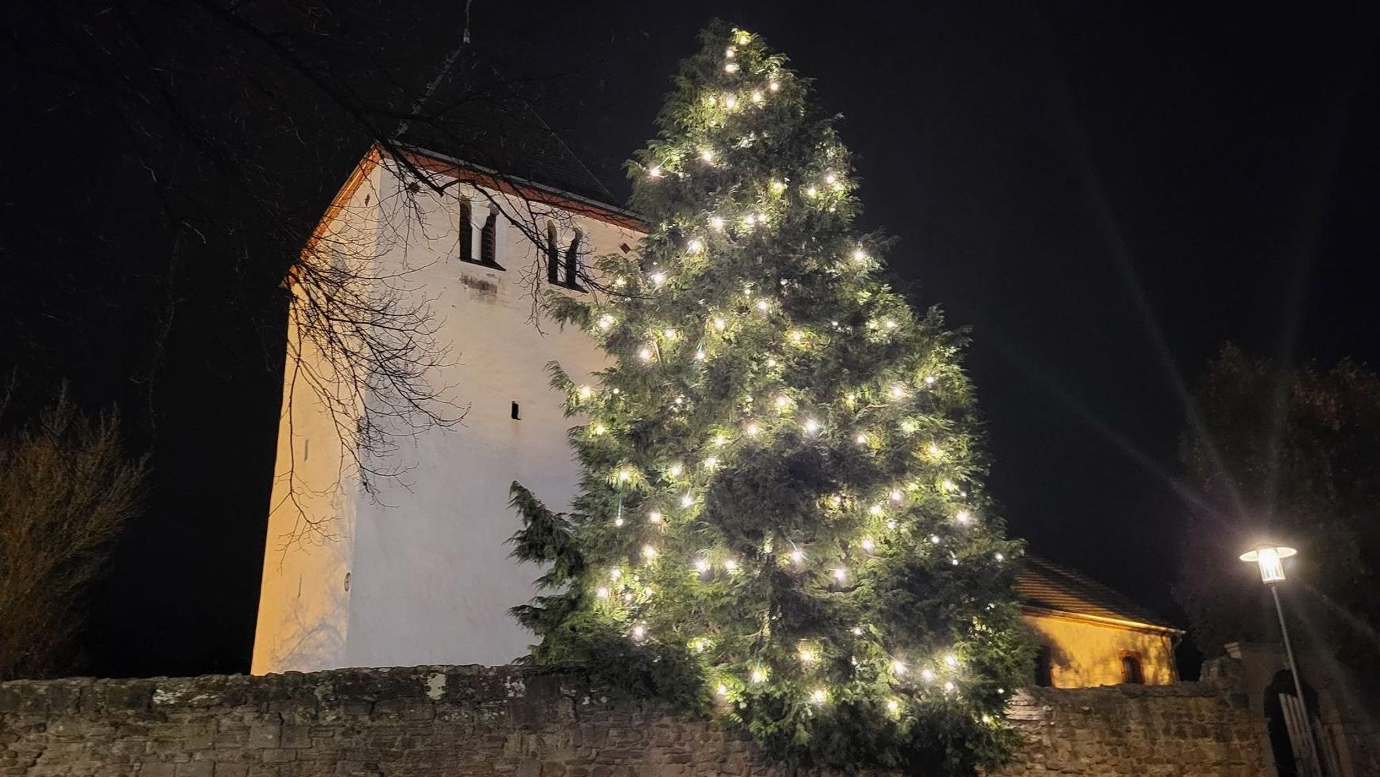 Ein Weihnachtsbaum leuchtet an der Alten Kirche in Mechernich.