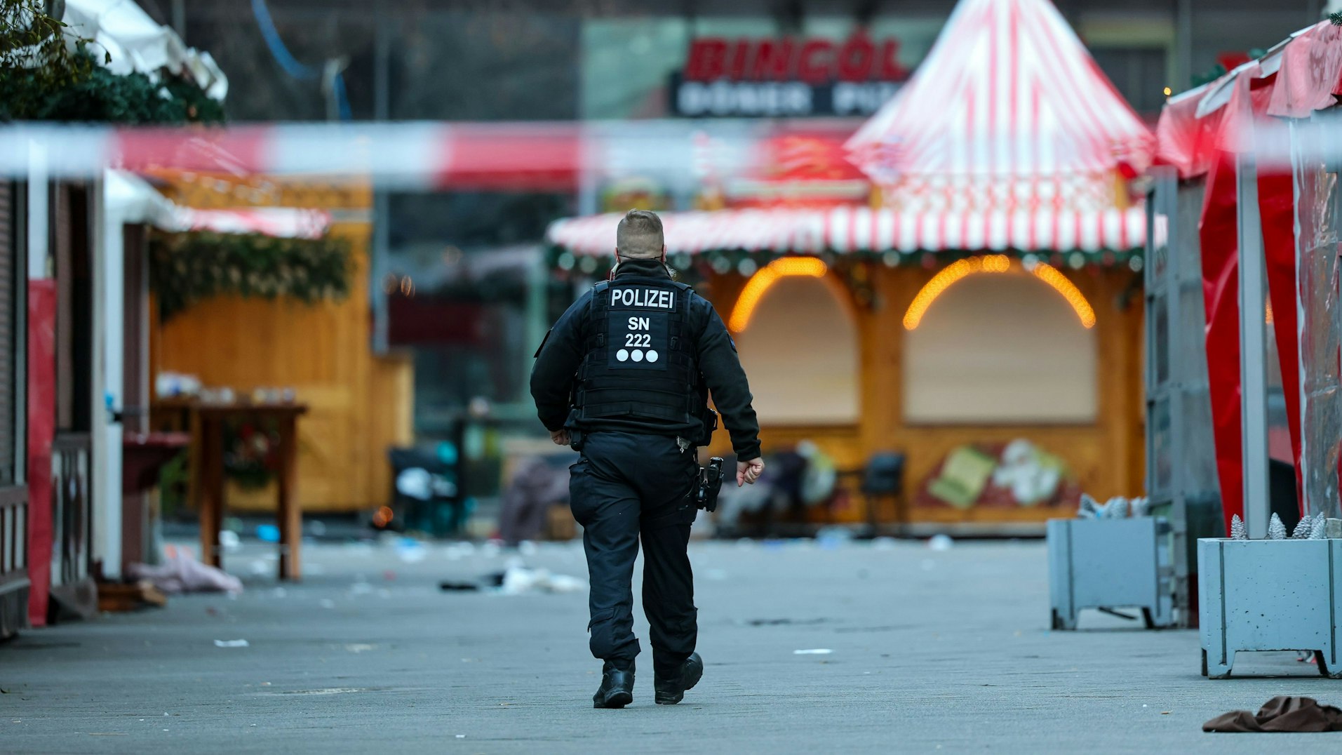 dpatopbilder - 21.12.2024, Sachsen-Anhalt, Magdeburg: Ein Polizist geht hinter einer Absperrung am Magdeburger Weihnachtsmarkt.
