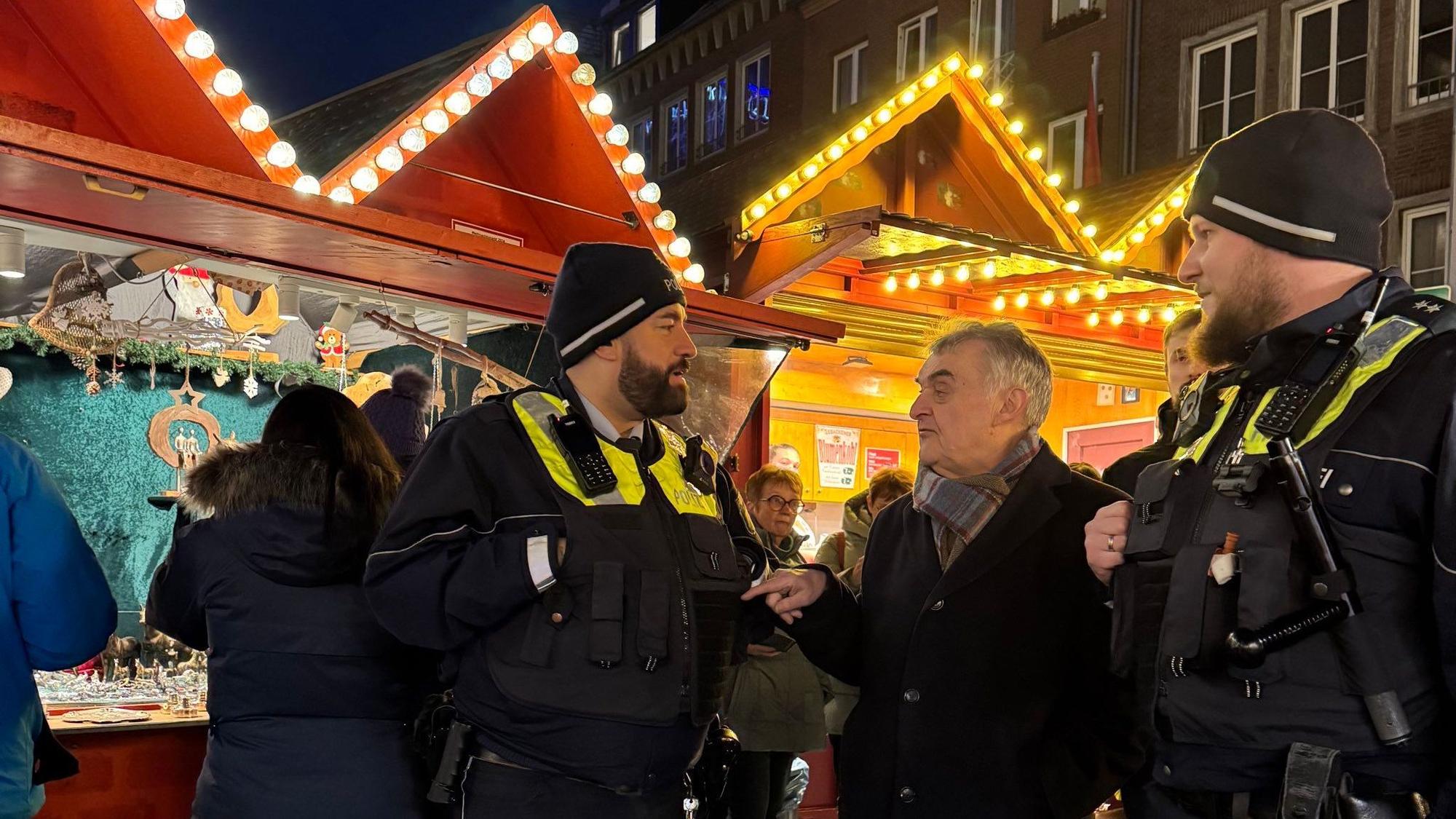 NRW-Innenminister Reul im Gespräch mit zwei Polizisten vor den Ständen eines Weihnachtsmarkts. Nach dem Anschlag von Magdeburg bleiben die Vorkehrungen für die Weihnachtsmärkte in Nordrhein-Westfalen zunächst unverändert. In Folge des Anschlags in Solingen und des Messerangriff in Siegen im August hatte Reul eine höhere Polizeipräsenz auf öffentlichen Veranstaltungen wie Weihnachtsmärkten angeordnet.