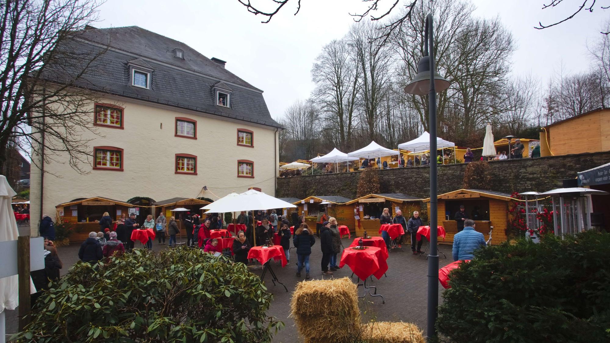 Das Burghaus, davor Tische und Schirme mit Menschen.