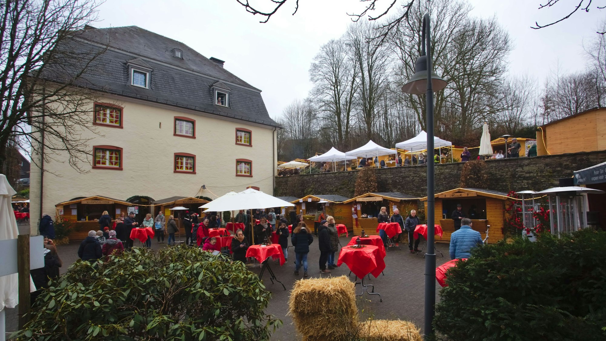 Das Burghaus, davor Tische und Schirme mit Menschen.