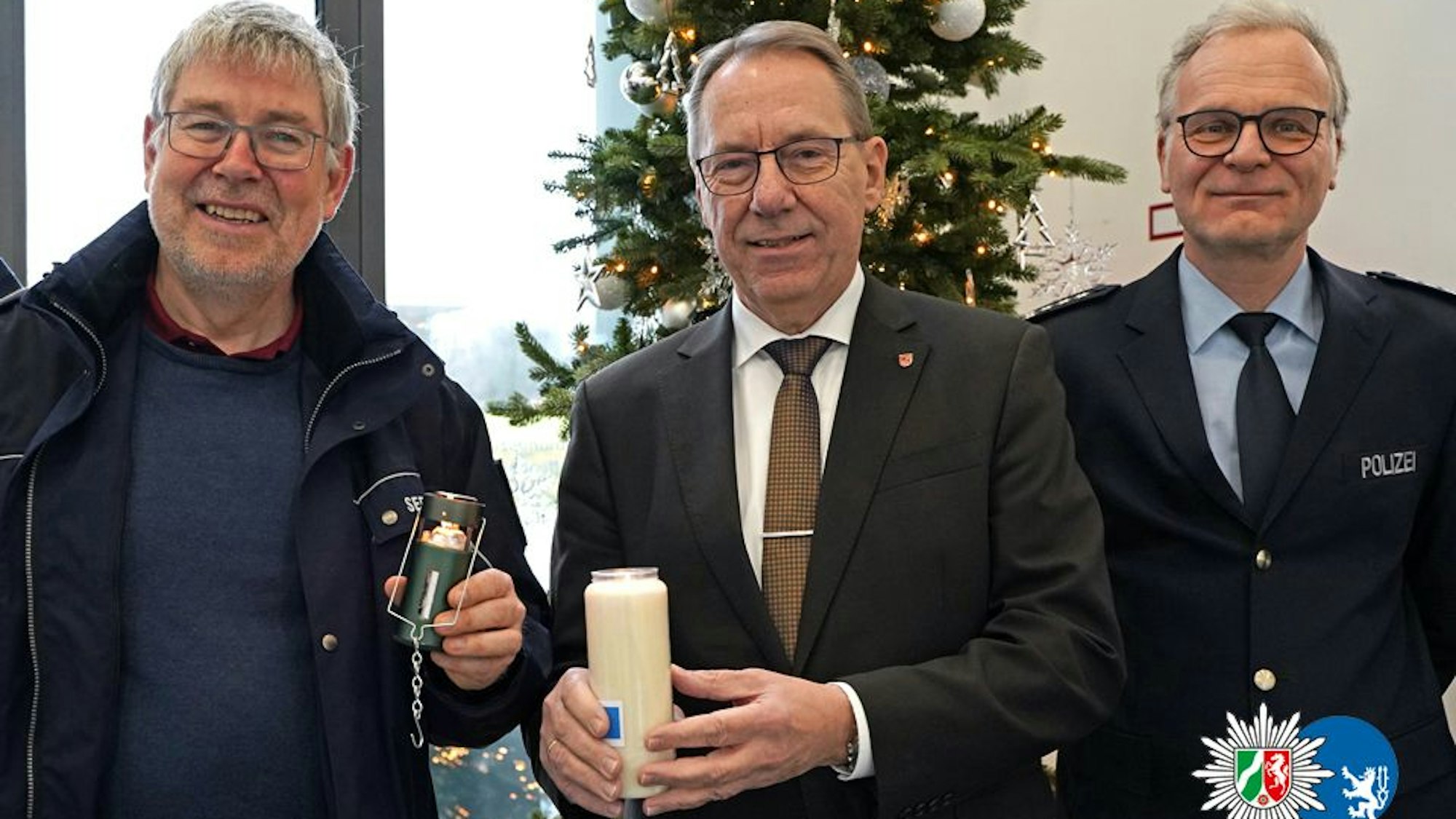 Seelsorger Norbert Schmitz, Landrat Jochen Hagt und Wachleiter Carsten Tschnerich stehen mit dem Friedenslicht auf der Wache Gummersbach.