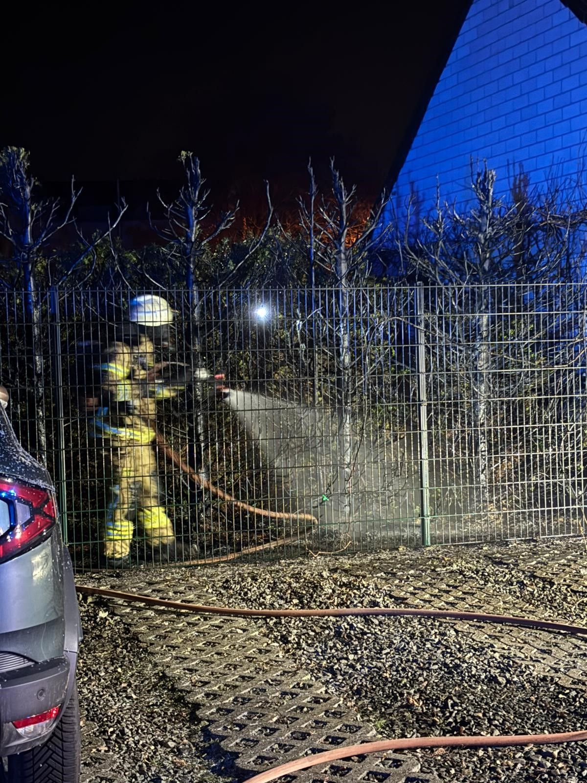 Ein Feuerwehrmann löscht einen Heckenbrand.