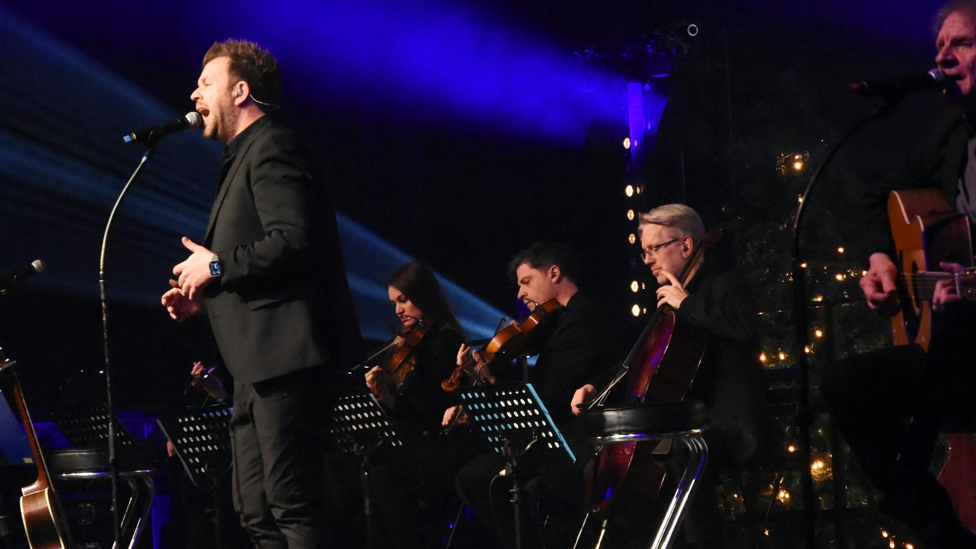 Ein Sänger und Streicher auf einer Bühne.