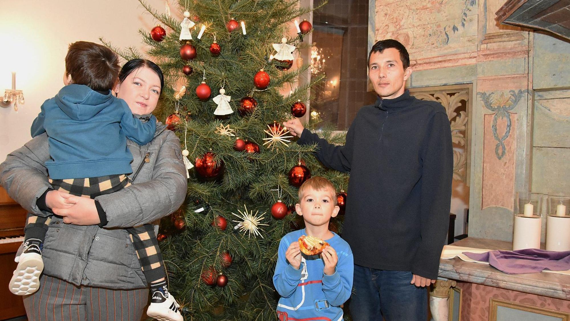 Eine ukrainische Familie steht in einer Kirche vor einem geschmückten Weihnachtsbaum.