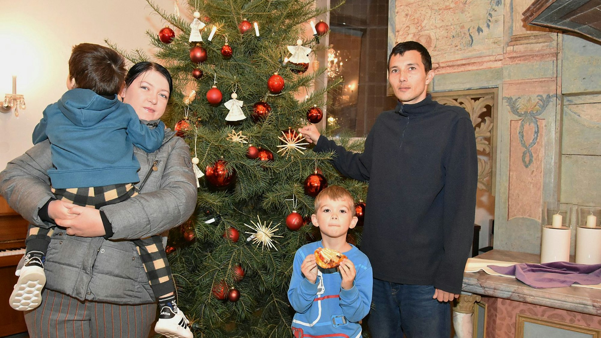 Eine ukrainische Familie steht in einer Kirche vor einem geschmückten Weihnachtsbaum.