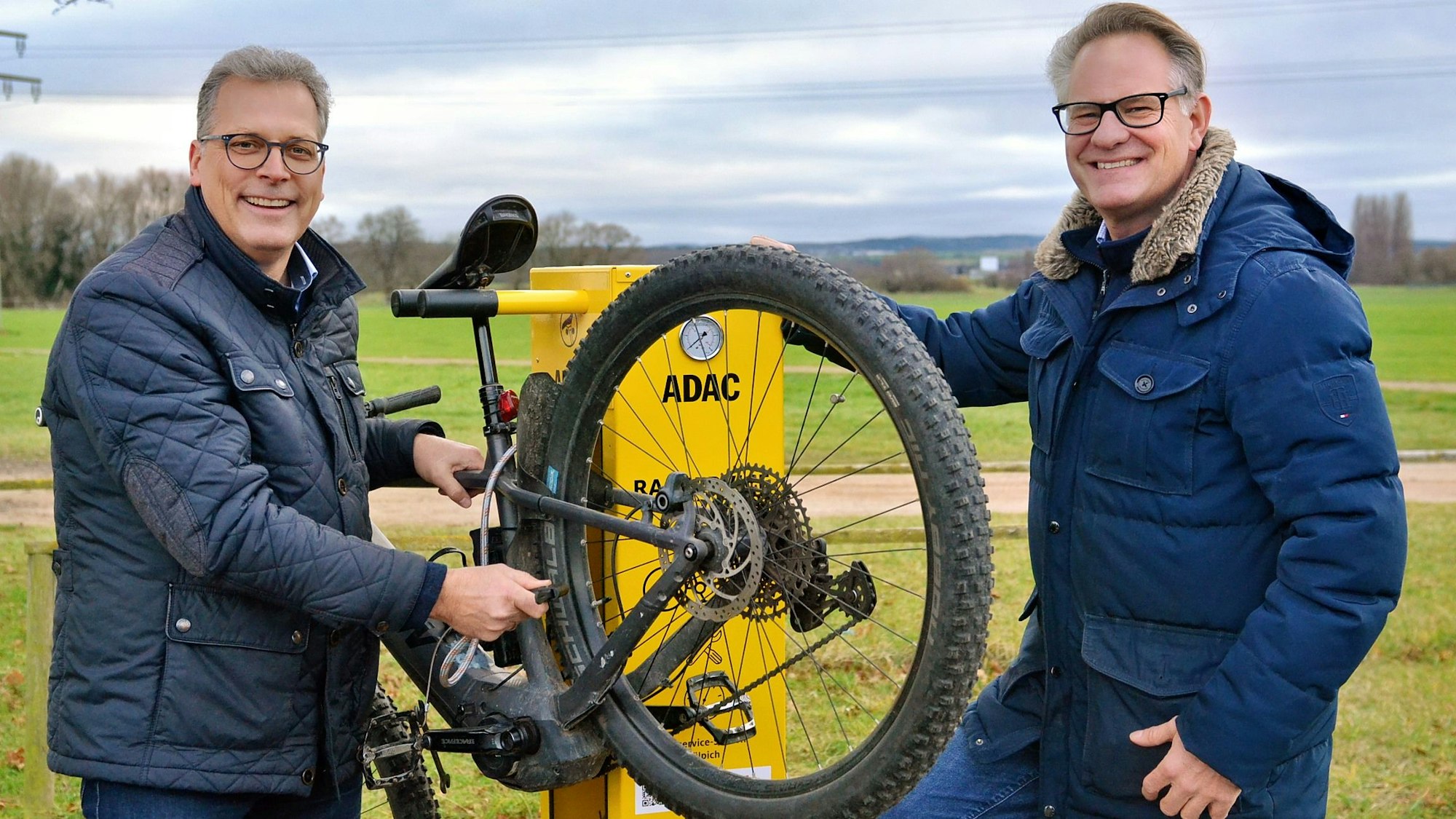 Zülpichs Bürgermeister Ulf Hürtgen und Projektleiter Roman Suthold stehen mit einem Fahrrad an einer Station.