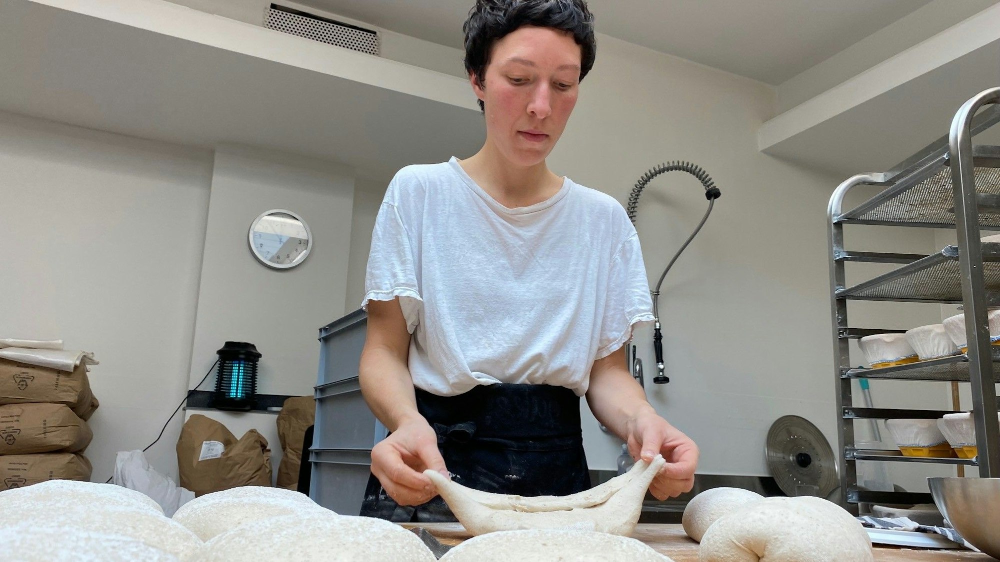 Zu sehen ist eine Frau, die Brotteig formt.