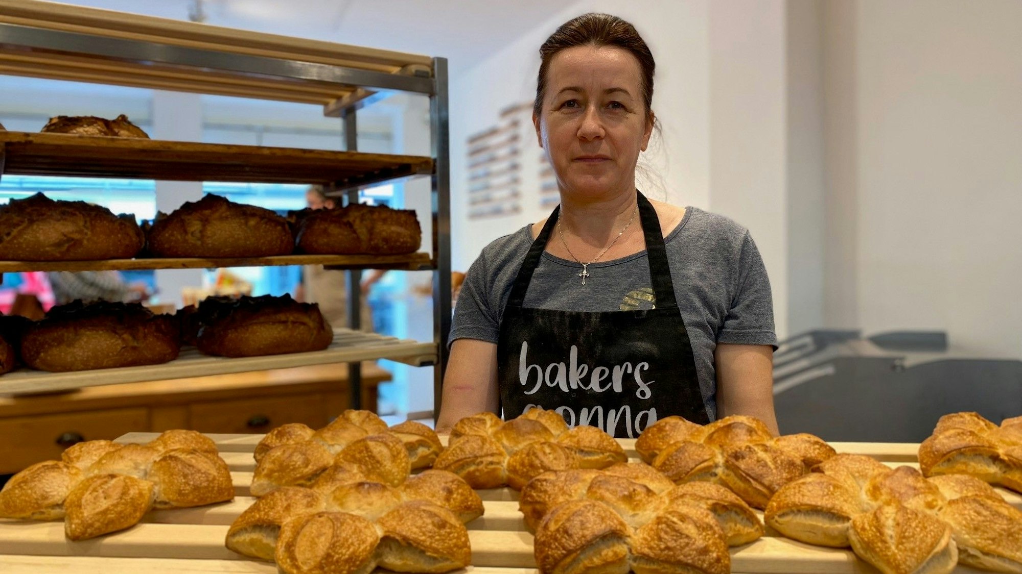 Zu sehen ist eine Frau, die ein großes Brett mit Backwaren hält.
