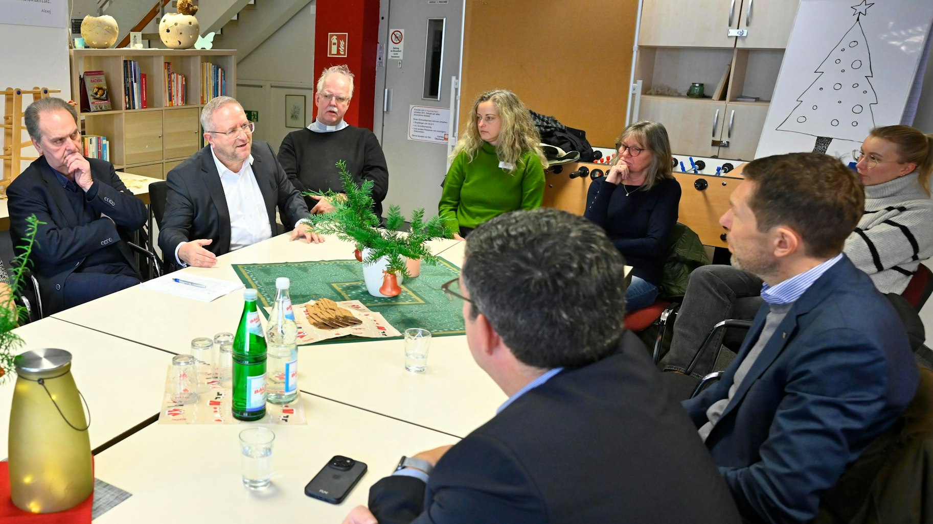 Eine Runde von Frauen und Männern sitzt an einem Tisch und bespricht sich.