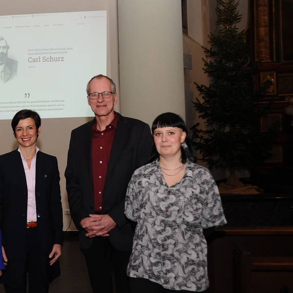 Drei Frauen und ein Mann stehen vor einer Leinwand in einer Kirche.