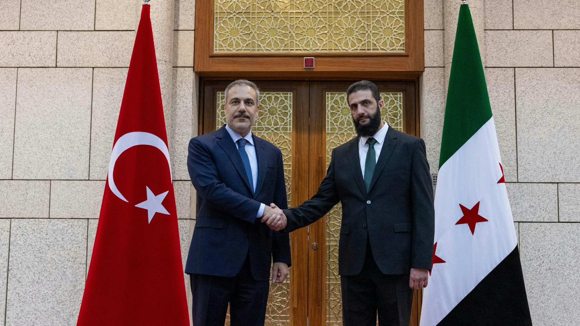 HANDOUT - 22.12.2024, Syrien, Damaskus: Auf diesem vom türkischen Außenministerium veröffentlichten Handout-Foto reicht der türkische Außenminister Hakan Fidan (l) Ahmed al-Sharaa, früher bekannt als Abu Mohammed al-Dschulani (r), die Hand bei ihrem Treffen in Damaskus, Syrien. Foto: Uncredited/Turkish Foreign Ministry Press Service/AP/dpa - ACHTUNG: Nur zur redaktionellen Verwendung im Zusammenhang mit einer Berichterstattung und nur mit vollständiger Nennung des vorstehenden Credits +++ dpa-Bildfunk +++