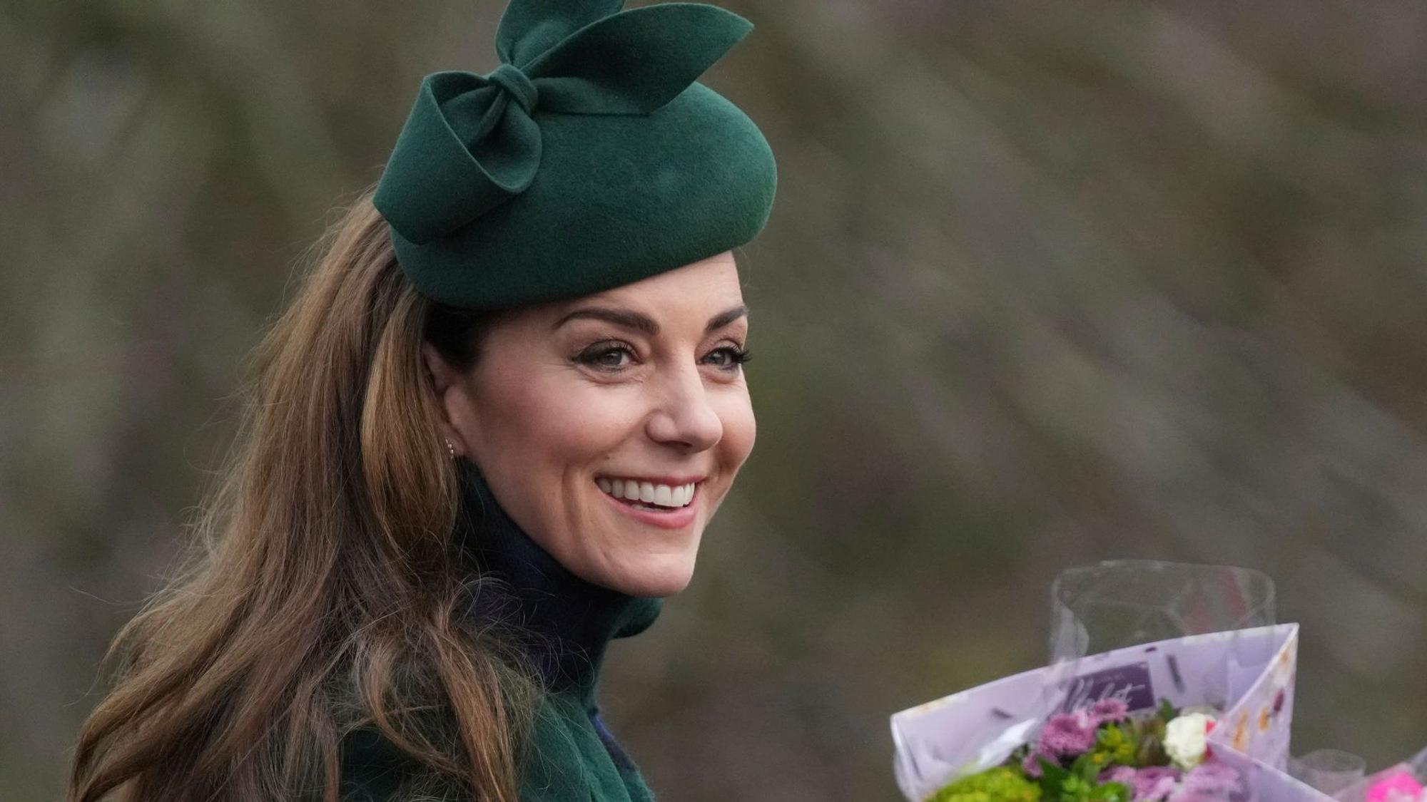 Prinzessin Kate lächelt und hält Blumen.