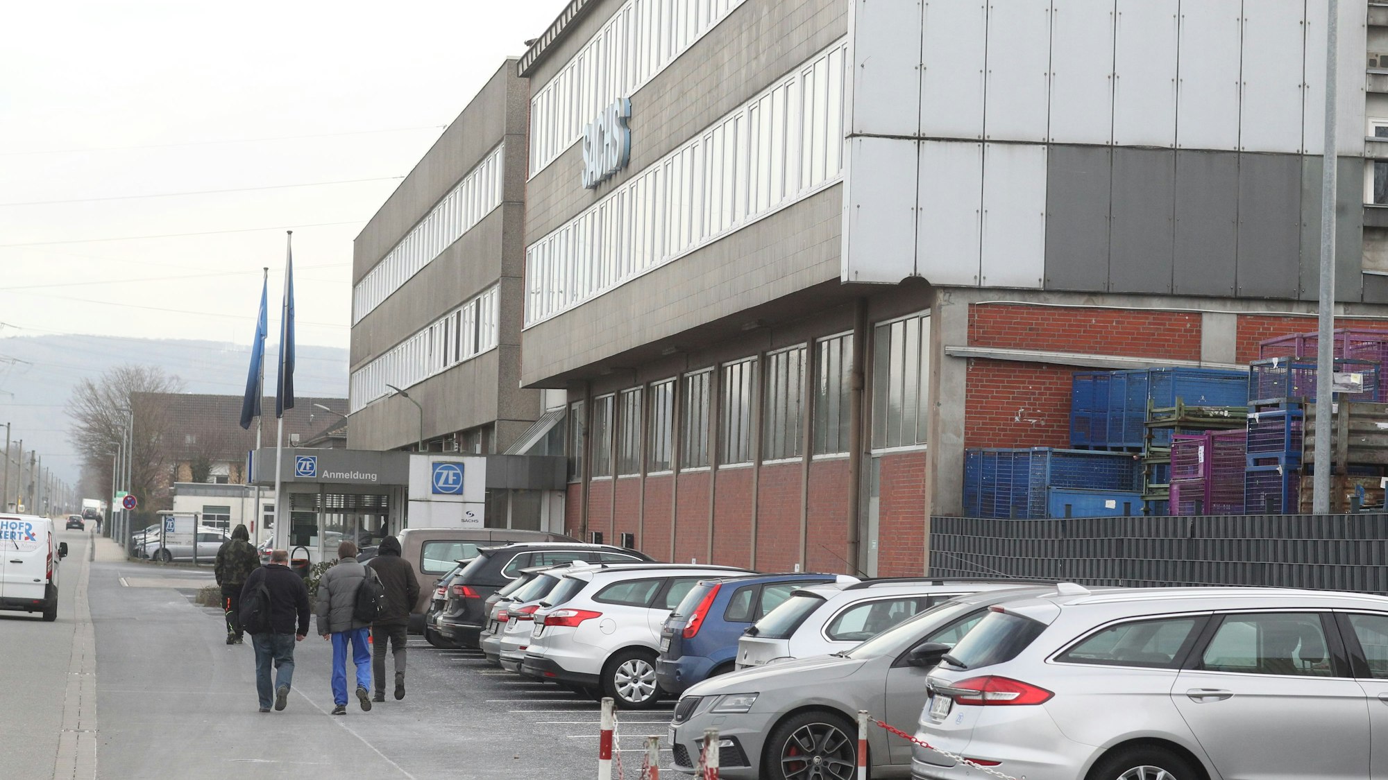 Menschen gehen an einem Industriegebäude vorbei.