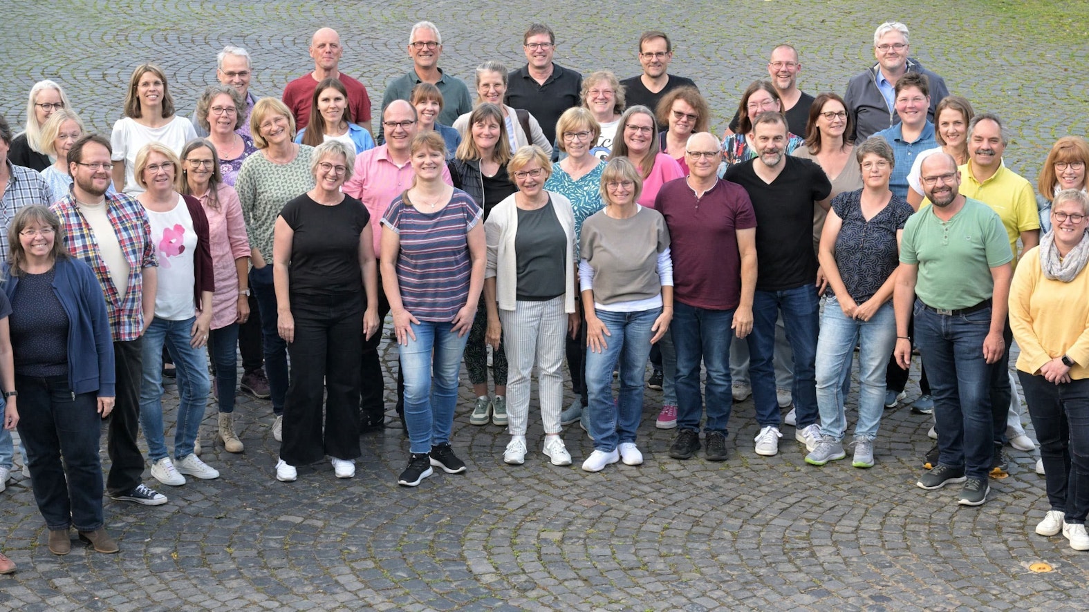 Der A-Cappella-Chor Kürten steht auf einem Platz mit Kopfsteinpflaster.