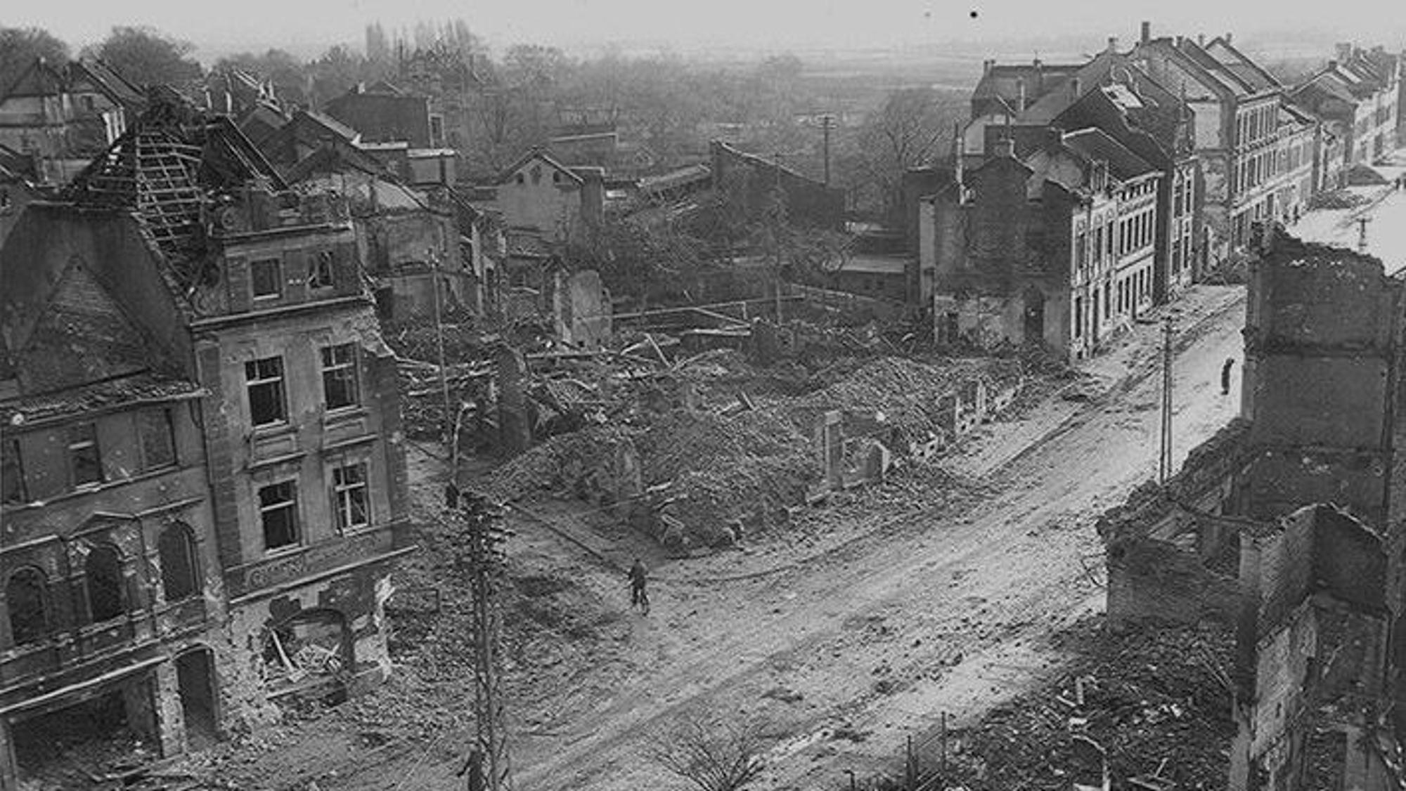 Zu sehen ist eine Schwarz-weiß-Aufnahme, die nach dem Bombenangriff 1944 entstanden ist und zerstörte Häuser zeigt.