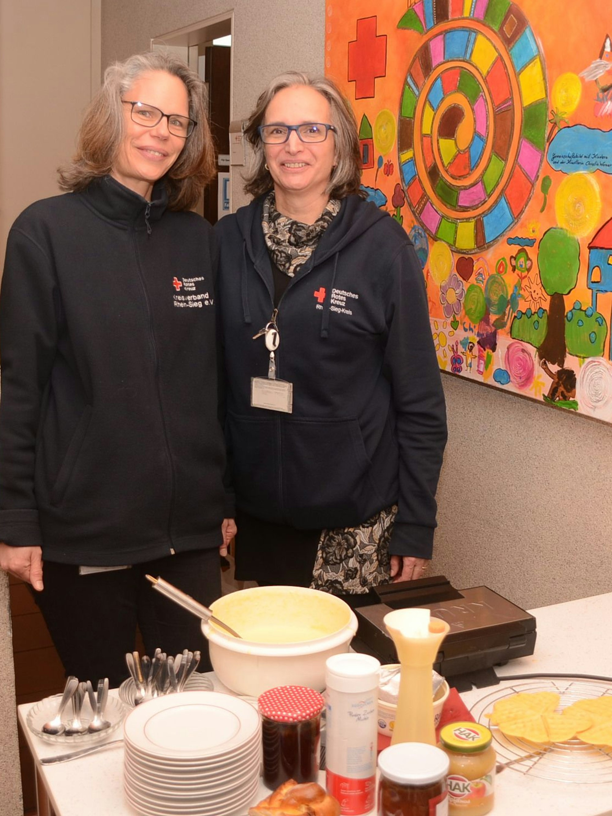 Zwei Frauen stehen hinter einem Tisch mit Teig und anderen Zutaten für Waffeln.