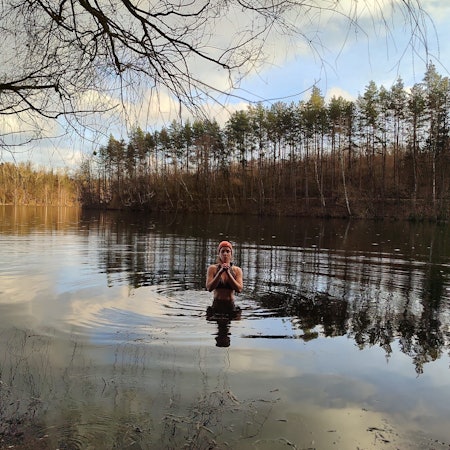 Zu sehen ist Janna Schillinger, die in das Wasser eines winterlichen Sees eintaucht.
