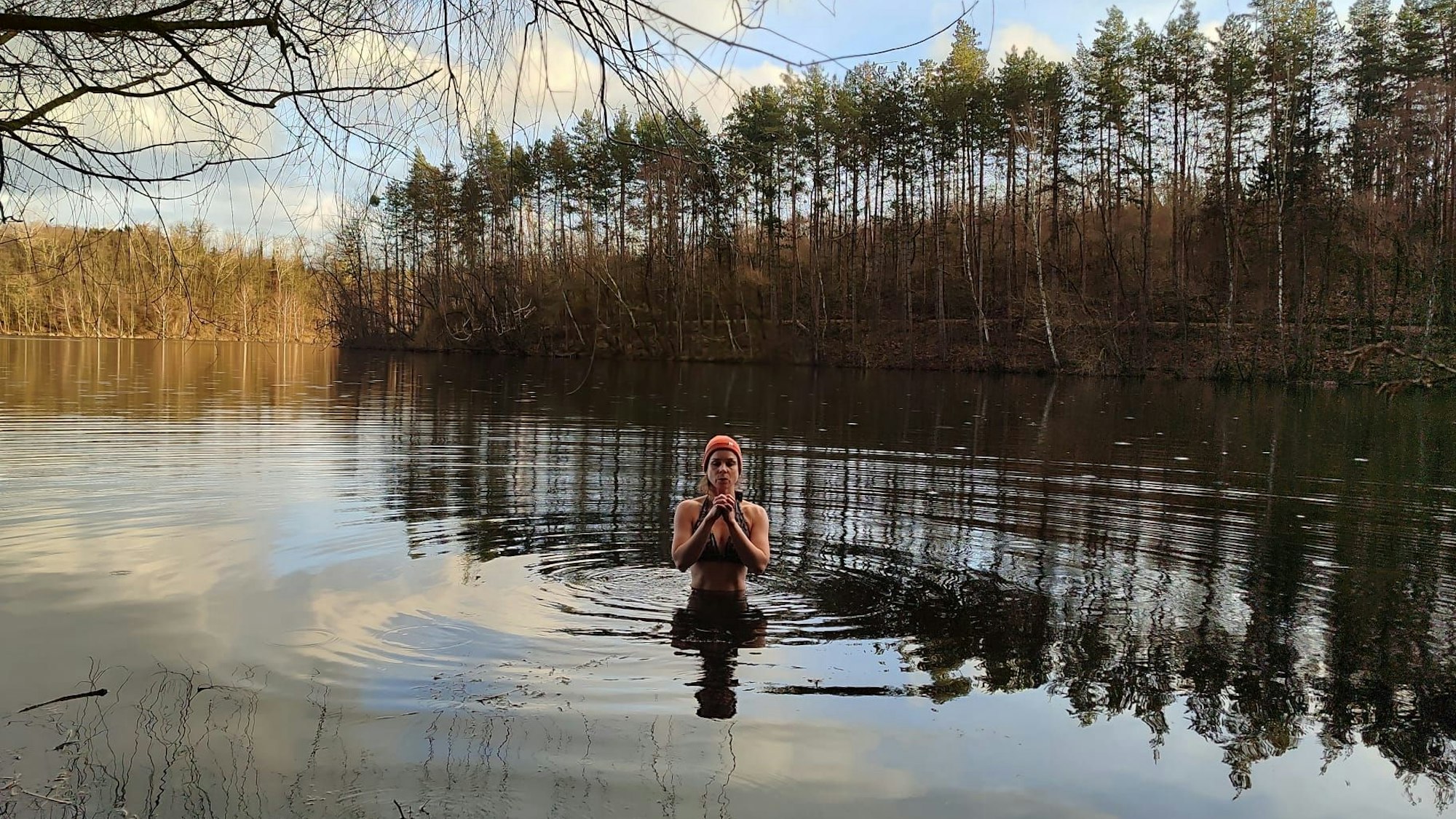 Zu sehen ist Janna Schillinger, die in das Wasser eines winterlichen Sees eintaucht.