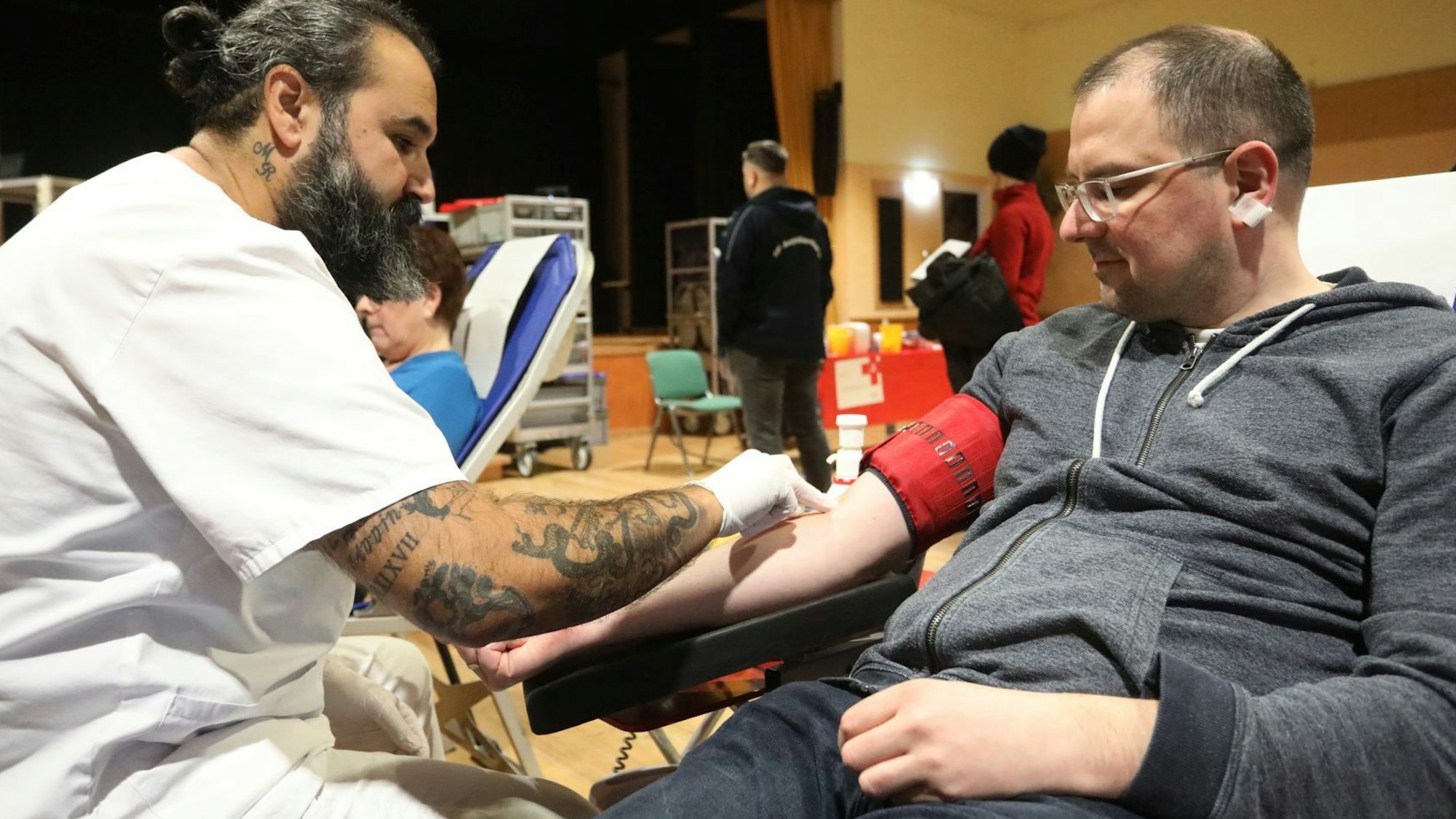 Ein Mann auf einer Liege bekommt den Zugang für eine Blutspende gelegt.