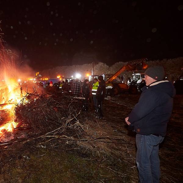 Zahlreiche Menschen haben sich in der Dunkelheit um ein Mahnfeuer versammelt.