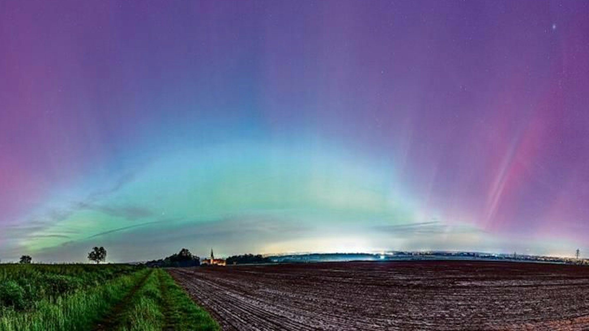 Polarlichter schimmern am Euskirchener Himmel über der Billiger Kirche.