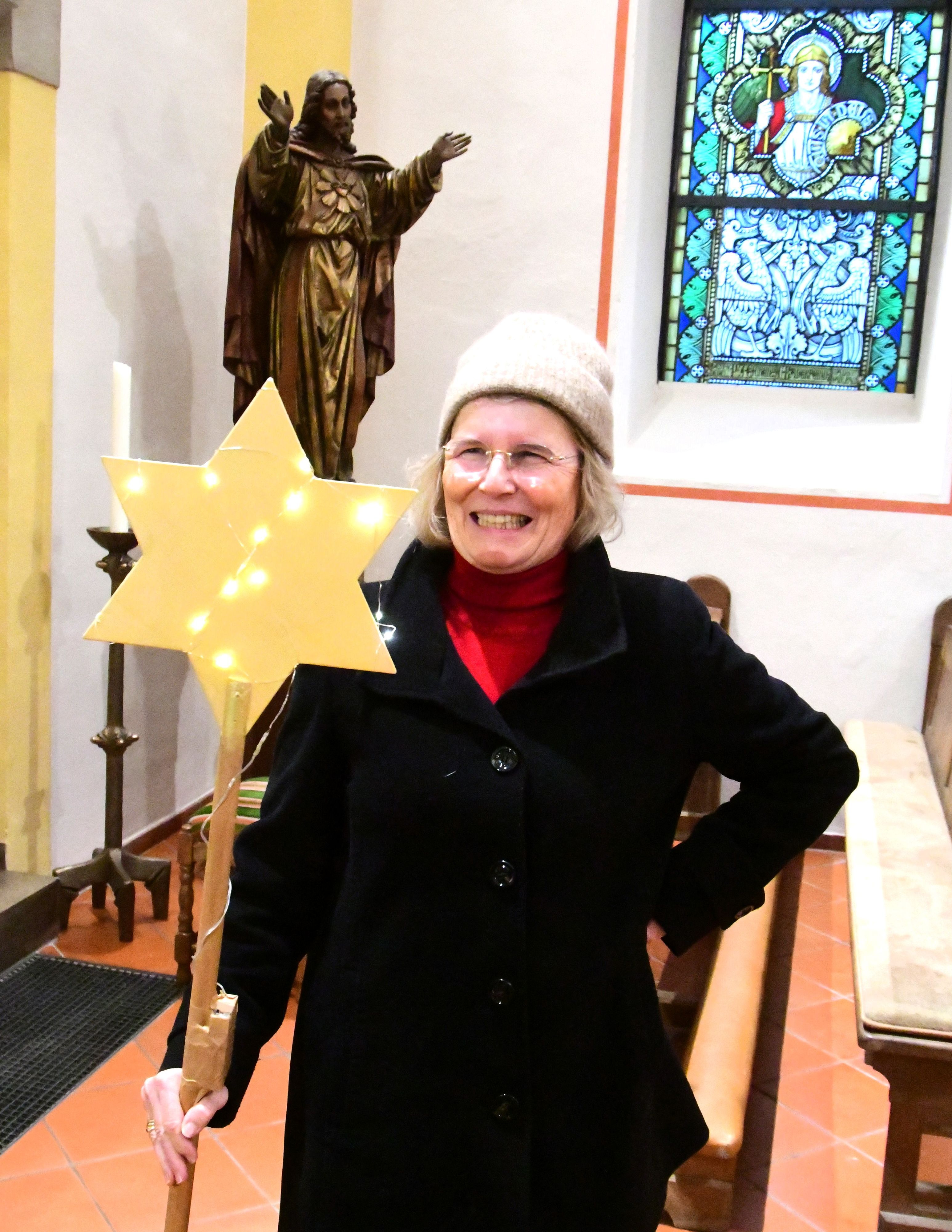 Antje Gräfin von Plettenberg steht in einer Kirche und hält einen mit LED-Lämpchen dekorierten Stern.