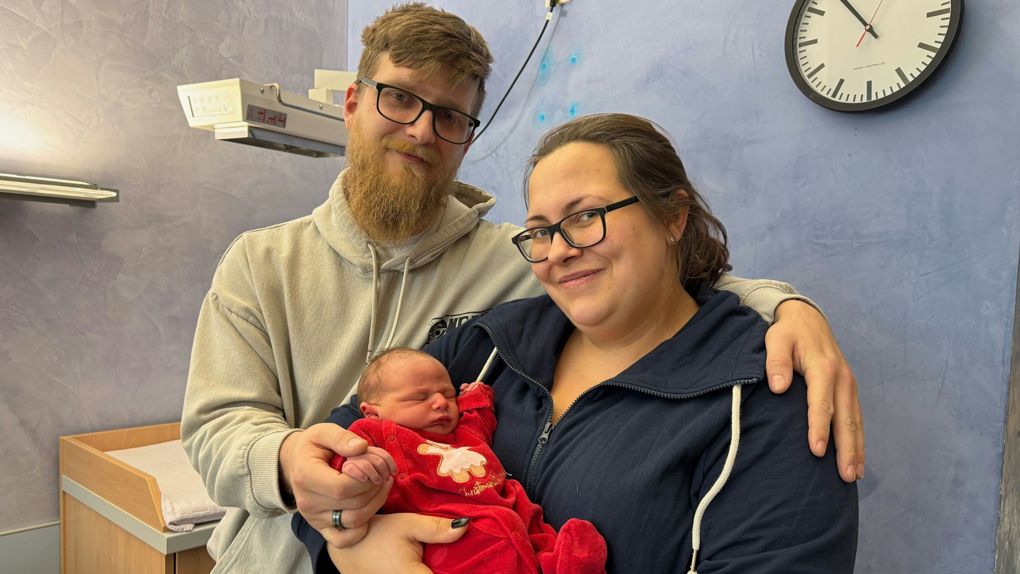 Vater und Mutter halten ihren neugeborenen Sohn namens Noel im Arm.