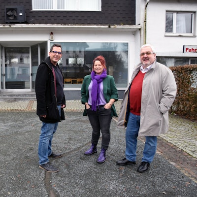 Das Foto zeigt ein leeres Ladenlokal, davor stehen Oliver Busch, Anja Mehren und Stefan Meisenberg.